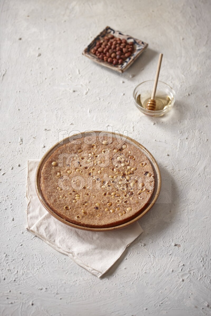 البسبوسة مع المكسرات والعسل علي خلفية بيضاء خشبية