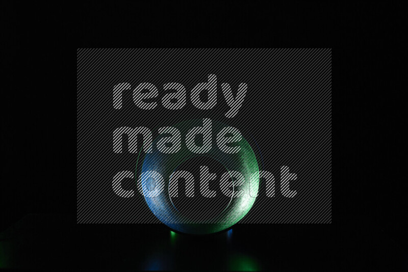 A reflector diffuser lamp shade dish with colored rim light against black background