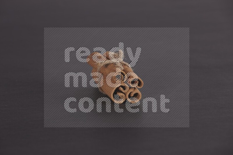 4 Cinnamon sticks stacked and bounded on black flooring