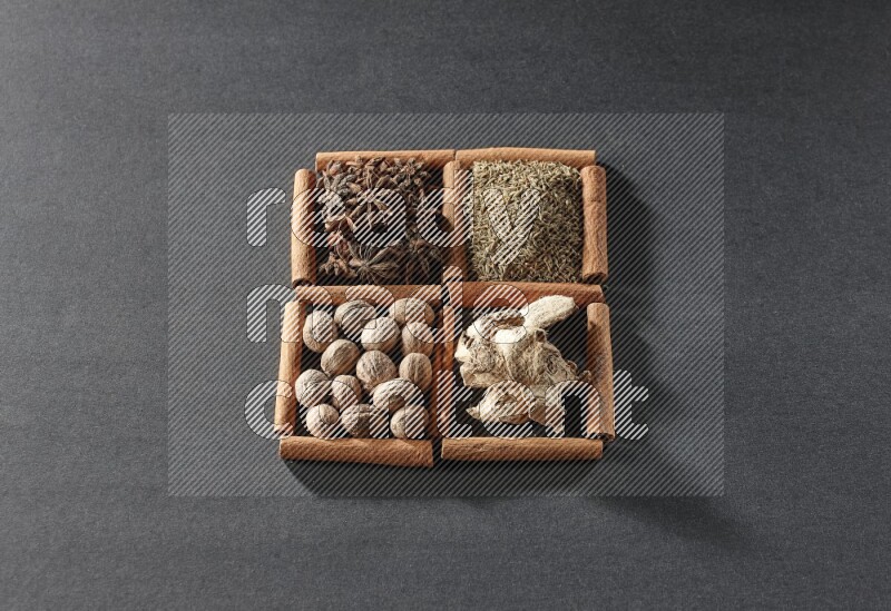 4 squares of cinnamon sticks full of star anise, cumin, dried ginger and nutmegs on black flooring