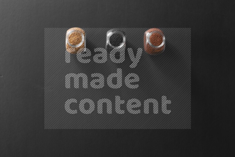 حبوب الخردل و حب الرشاد وحبة البركة في أوعية زجاجية علي خلفية سوداء