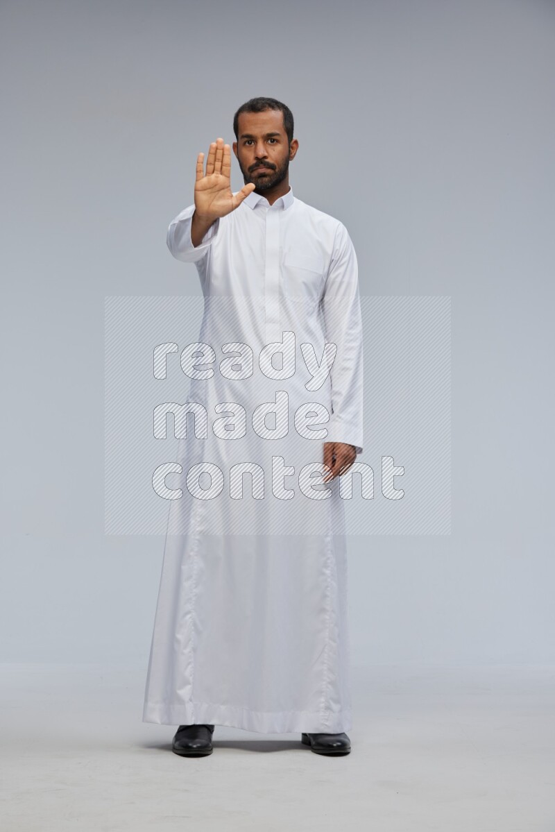 Saudi man Wearing Thob standing interacting with the camera on Gray background