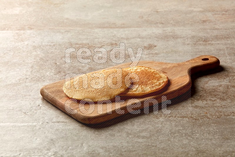 Two stacked plain pancakes on a wooden board on beige background