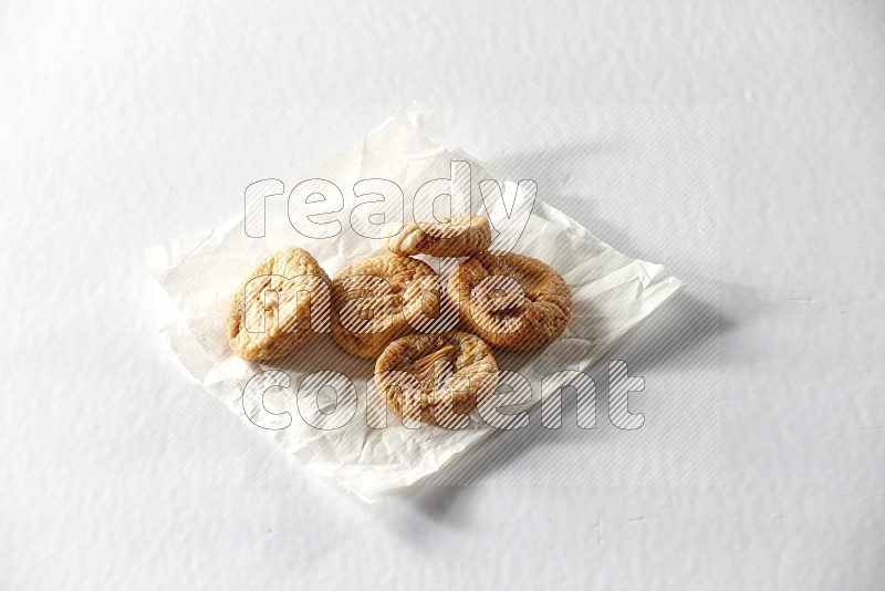 Dried figs on a crumpled piece of paper on a white background in different angles