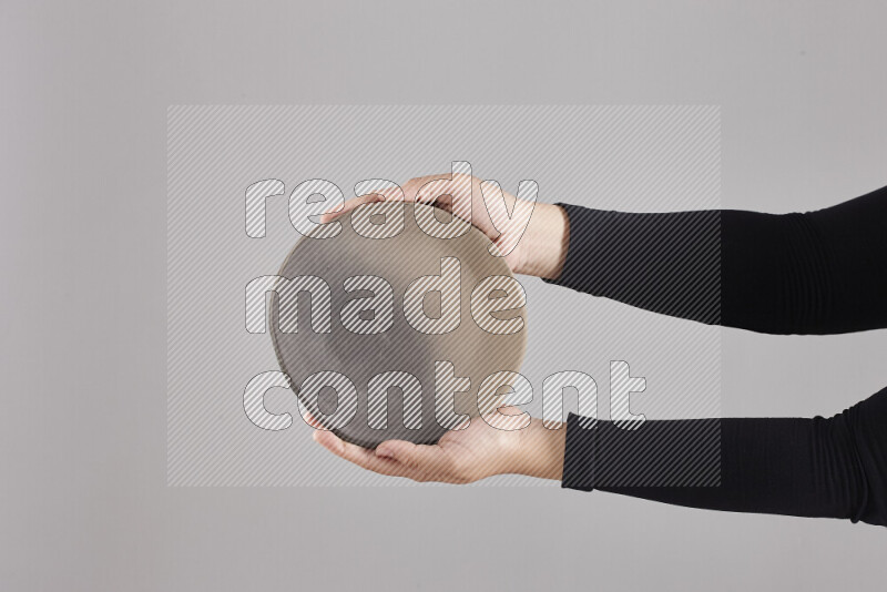 A woman in black abaya holding different pottery essentials in different positions