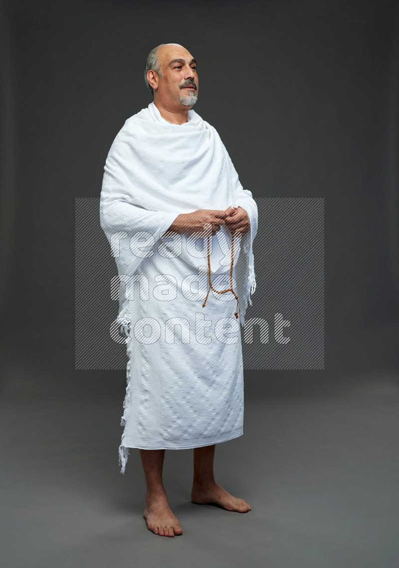 A man wearing Ehram Standing holding rosary on gray background