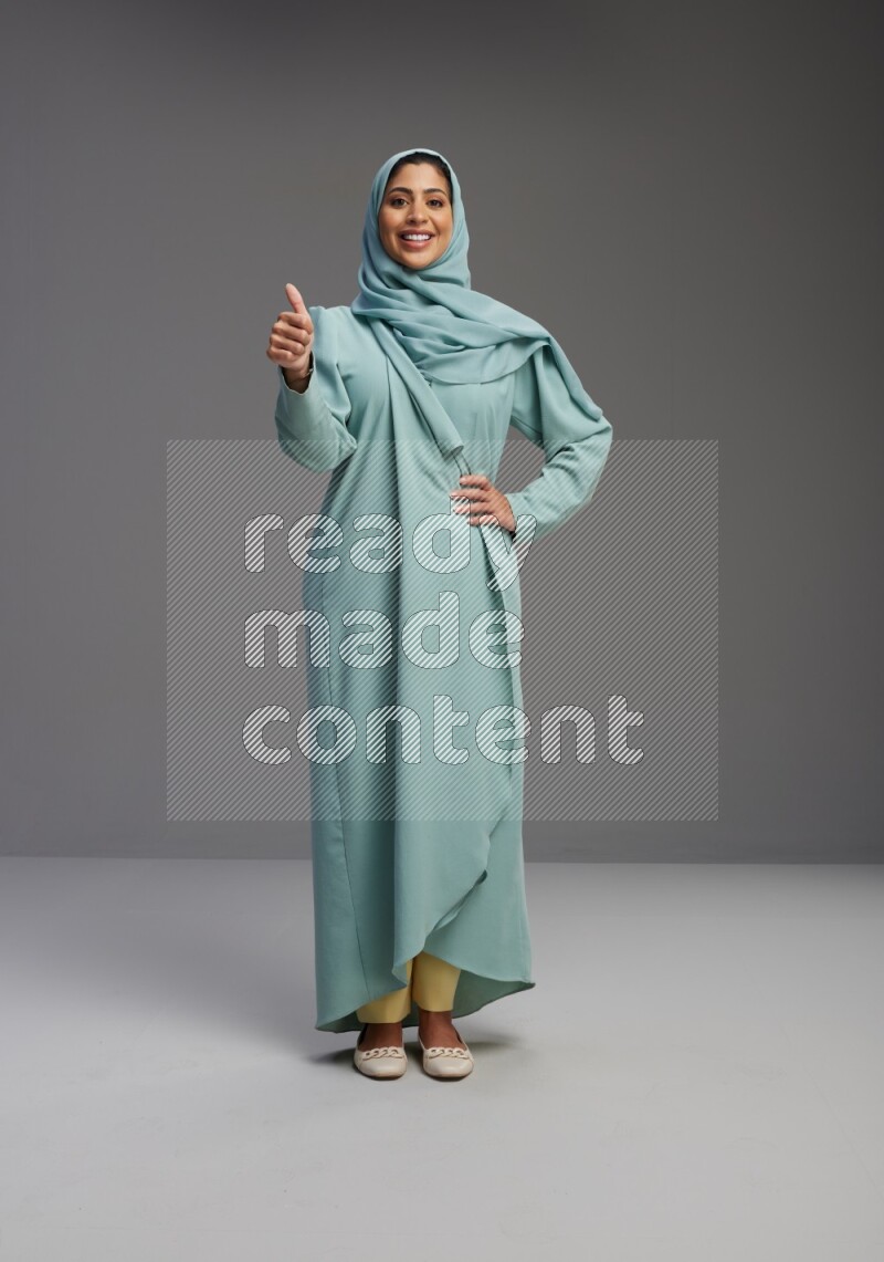 Saudi Woman wearing Abaya standing interacting with the camera on Gray background