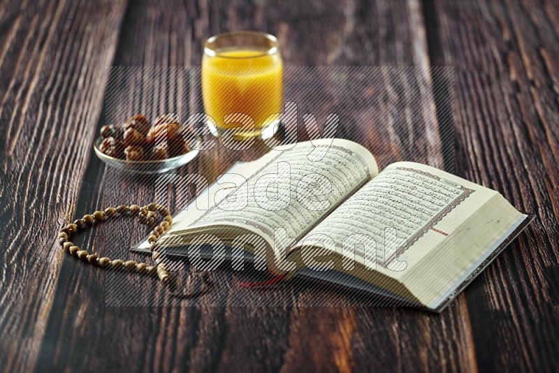 Quran with dates, prayer beads and different drinks all placed on wooden background