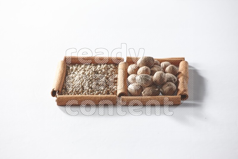 2 squares of cinnamon sticks full of white pepper and nutmegs on white flooring