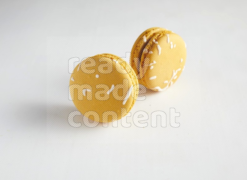 45º Shot of two Yellow Piña Colada macarons on white background