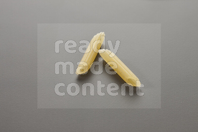 Mini penne pasta on grey background