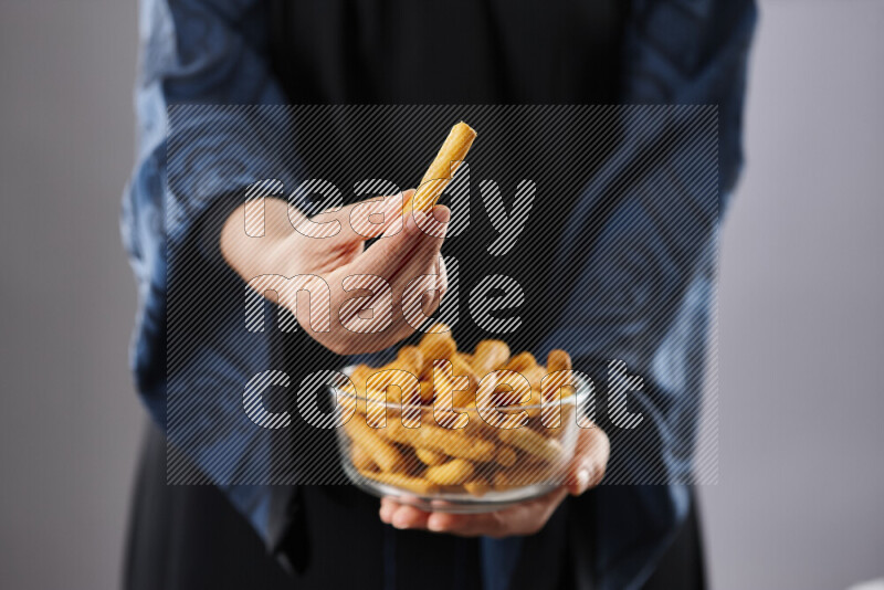 Woman in abaya holding different kinds of snacks in different positions