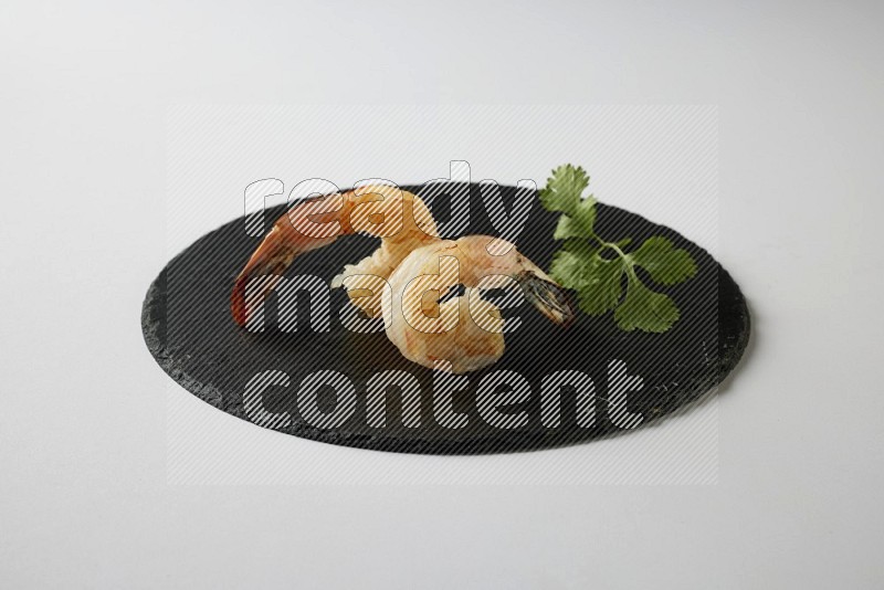 two grilled shrimp  on a black slate direct  on a white back ground