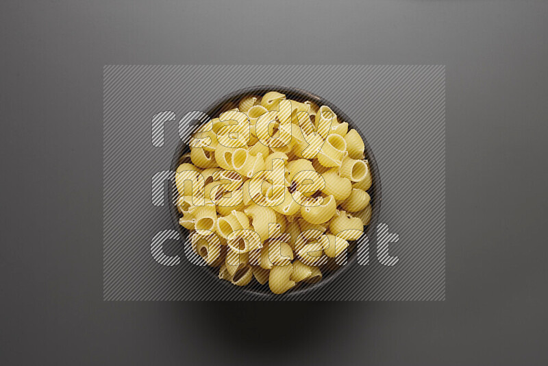 Pipe pasta in a pottery bowl on grey background