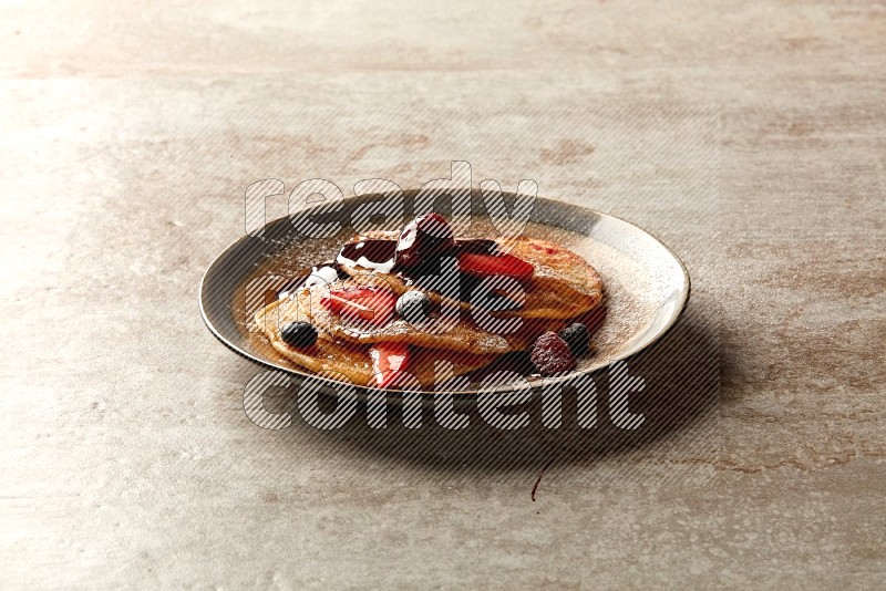 Three stacked mixed berries pancakes in a bicolor plate on beige background