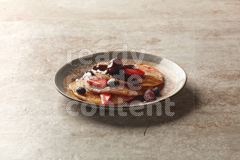 Three stacked mixed berries pancakes in a bicolor plate on beige background
