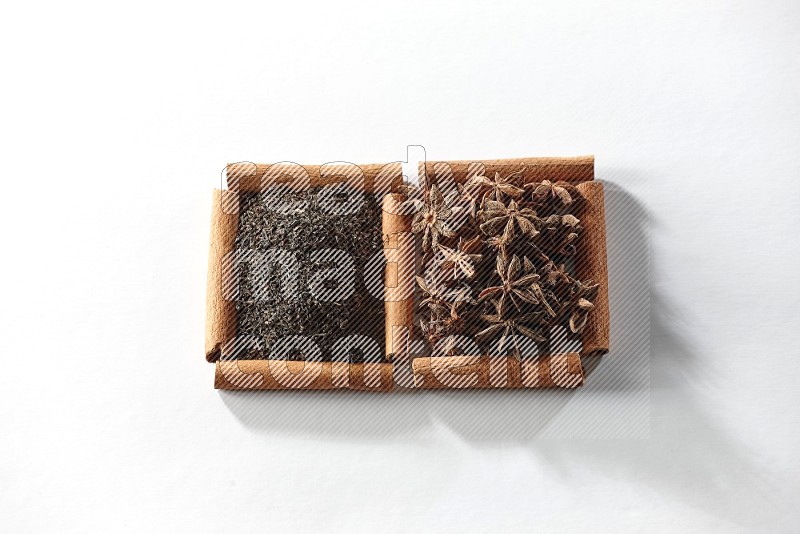 2 squares of cinnamon sticks full of star anise and black tea on white flooring