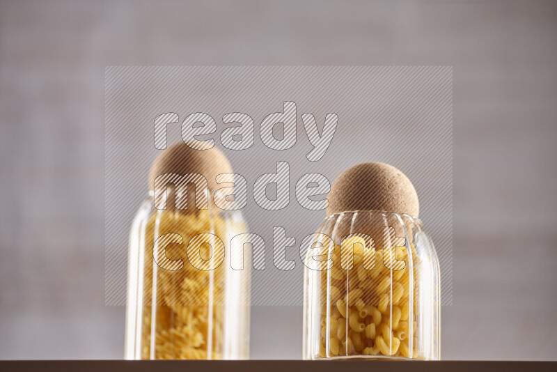 Raw pasta in glass jars on beige background