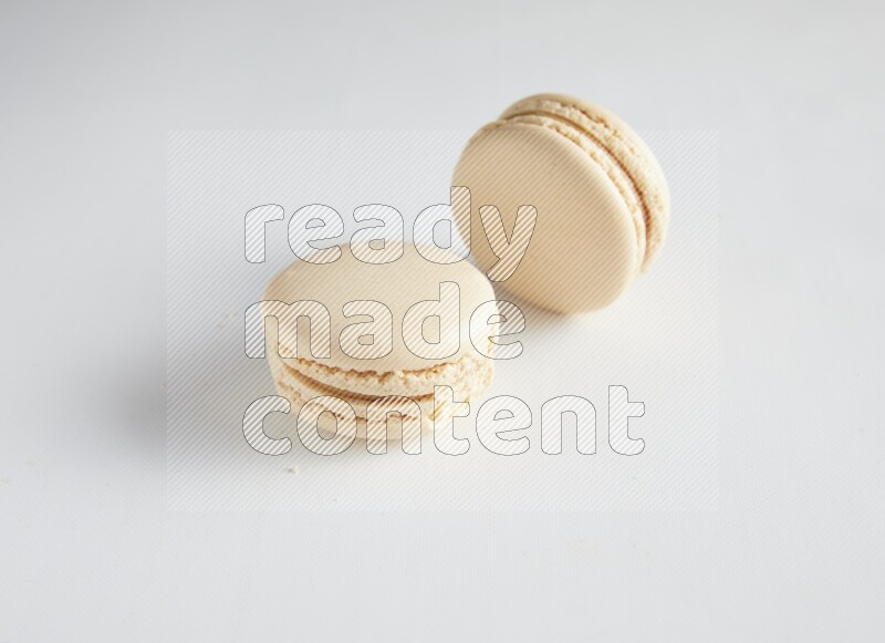 45º Shot of two White Caramel fleur de sel macarons on white background