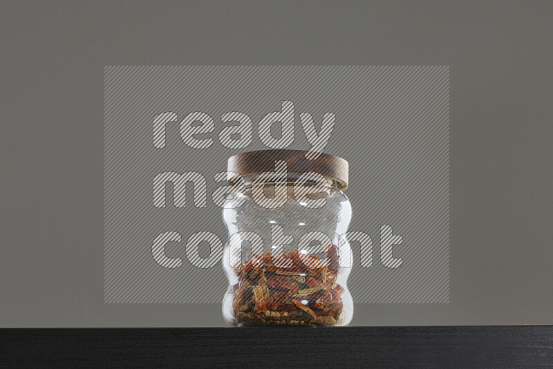 Chili pepper in a glass jar on black background