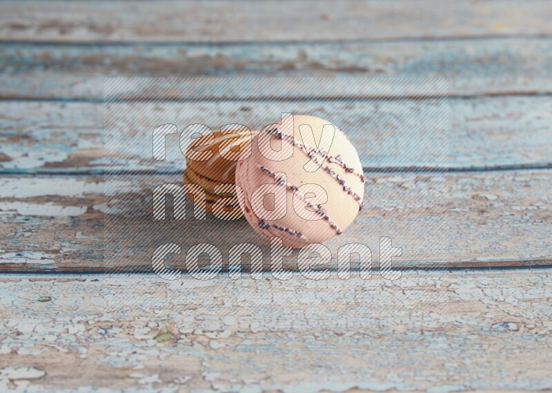 45º Shot of of two assorted Brown Irish Cream, and pink orange blossom  macarons on light blue background