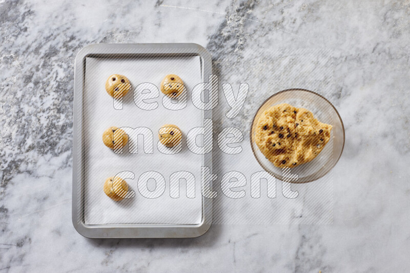 Cookies step by step with its ingredient, flour, butter, brown sugar, egg, vanilla extract, white sugar, chocolate chips and baking soda on grey marble background