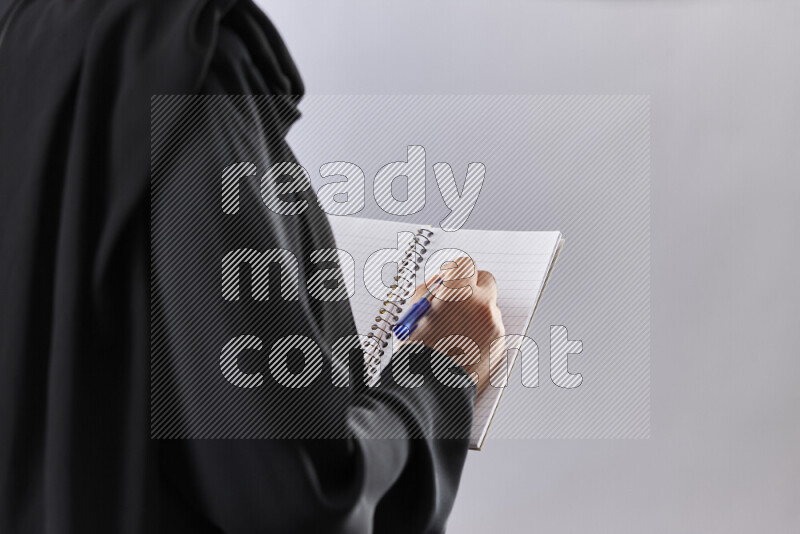 A woman in abaya holding books and a board in different positions (back to school)