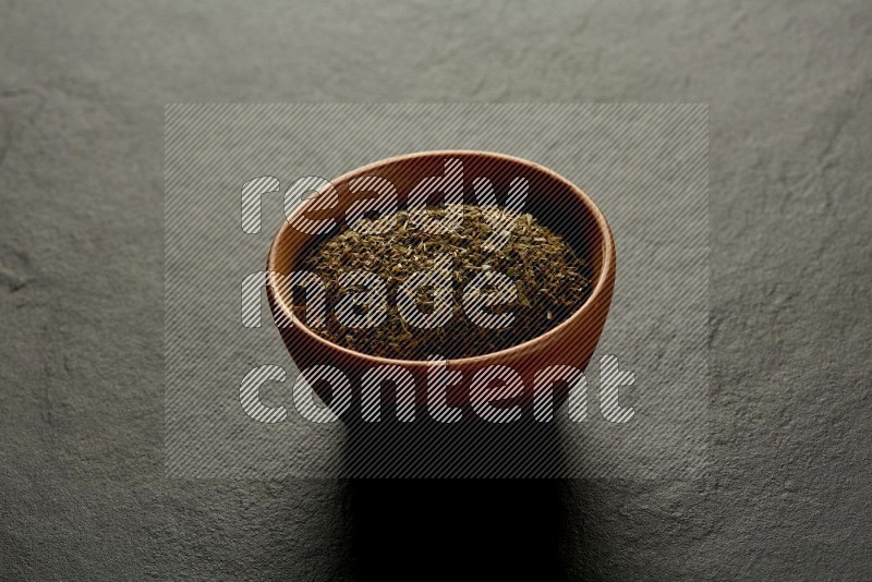 wooden round sauce bowl filled with herbs on grey textured countertop