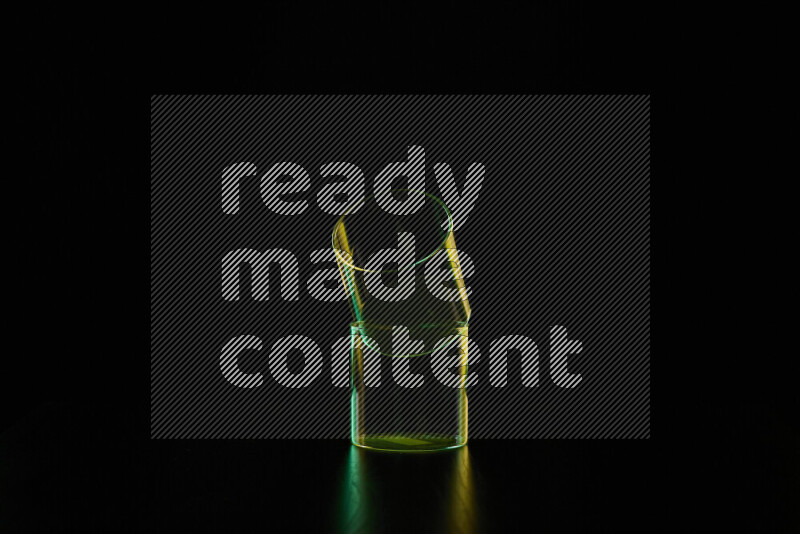 Glassware with rim light in green and yellow against black background