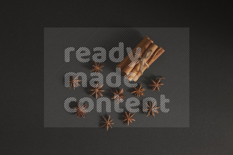 Cinnamon sticks stacked and bounded and star anise on black background