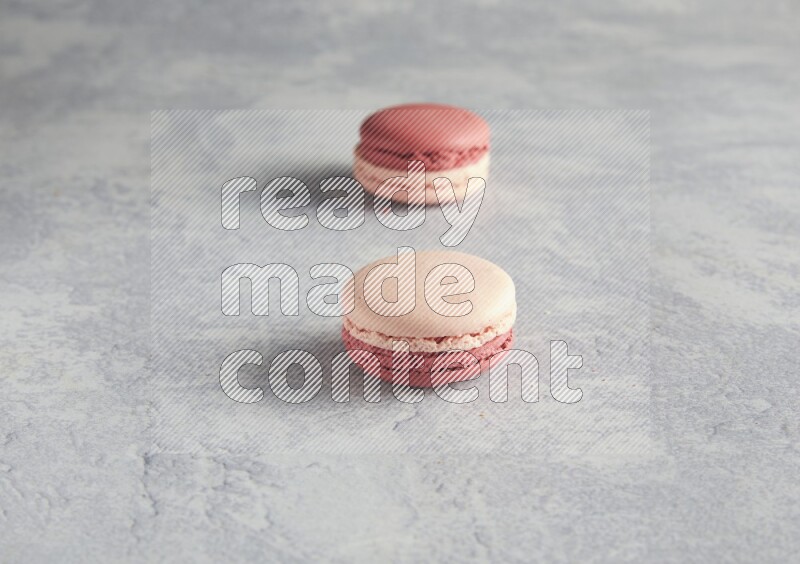 45º Shot of two Pink Litchi Raspberry macarons  on white  marble background