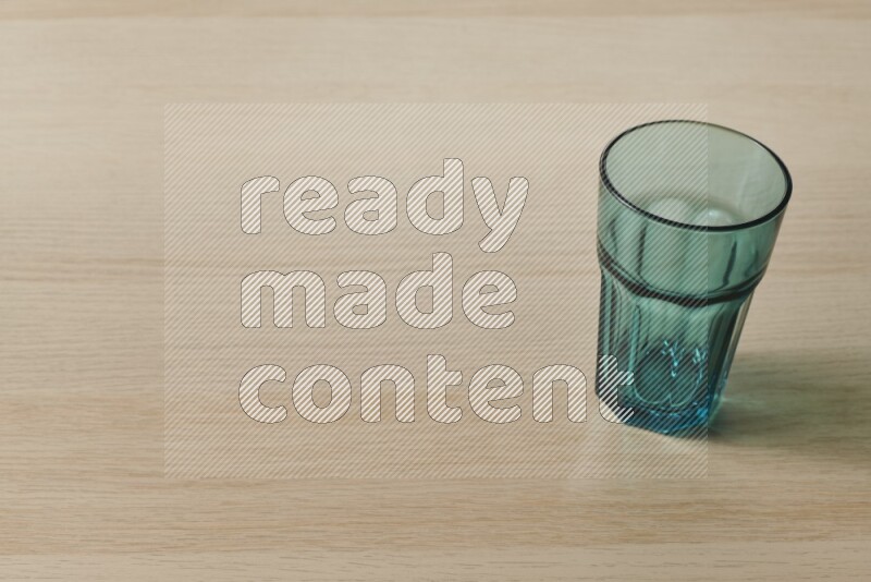 A turquoise glass cup on light wooden background