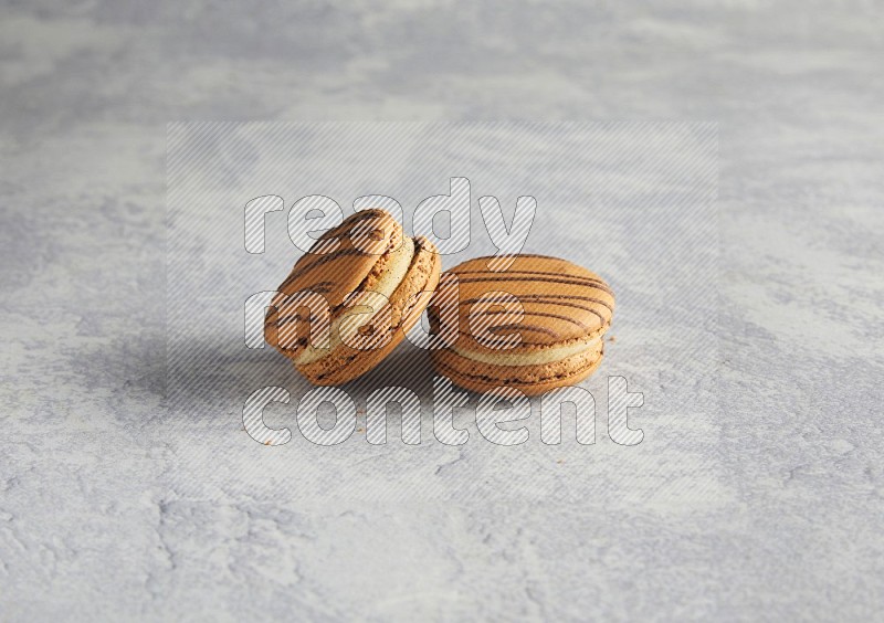 45º Shot of two light brown  Almond Cream macarons  on white  marble background