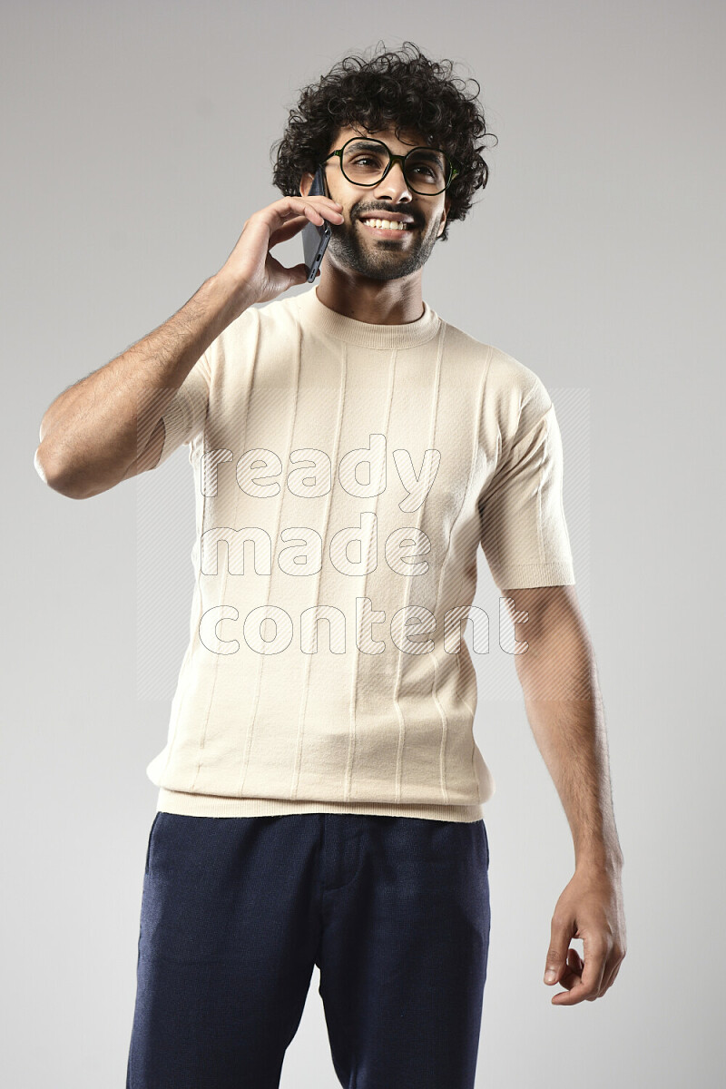 رجل يرتدي ملابس كاجوال يتحدث في الهاتف علي خلفية بيضاء