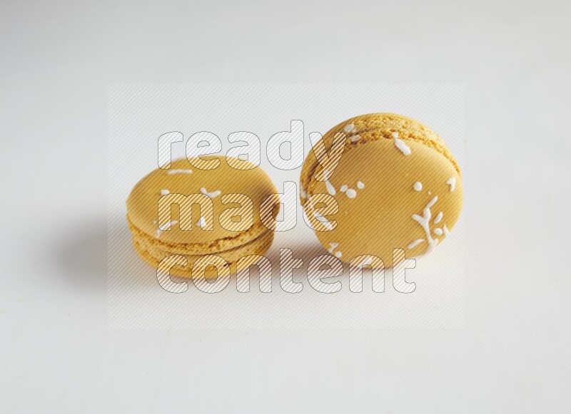 45º Shot of two Yellow Piña Colada macarons on white background
