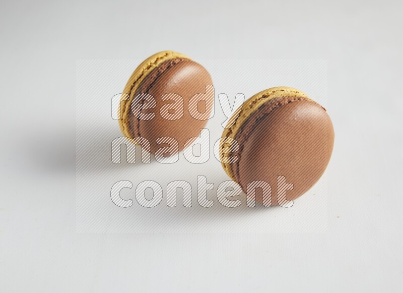 45º Shot of two Yellow and Brown Chai Latte macarons on white background