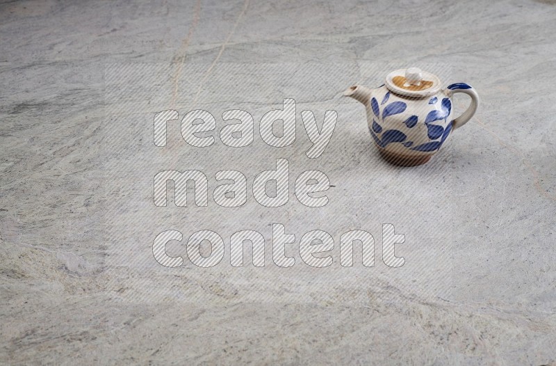 A Pottery Teapot On Grey Marble Flooring