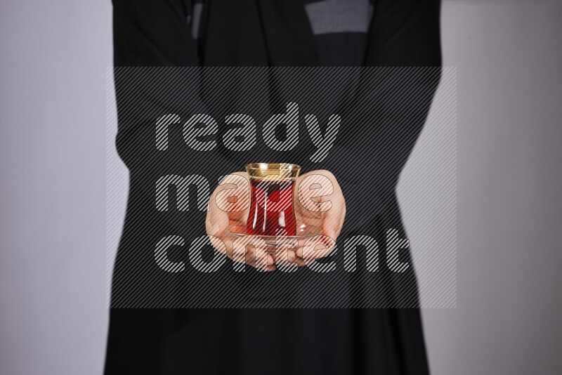 A woman in black abaya holding different glassware in different positions