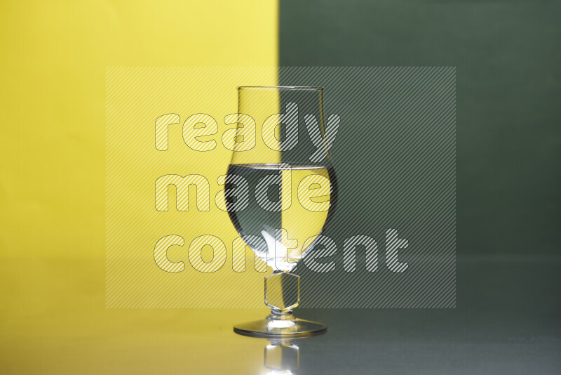 The image features a clear glassware filled with water, set against yellow and dark green background