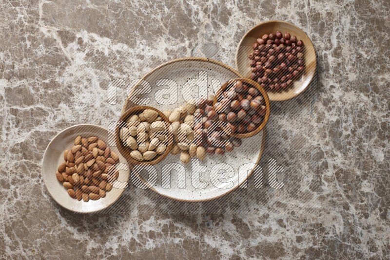 Nuts in pottery plates and wooden bowls in a light setup