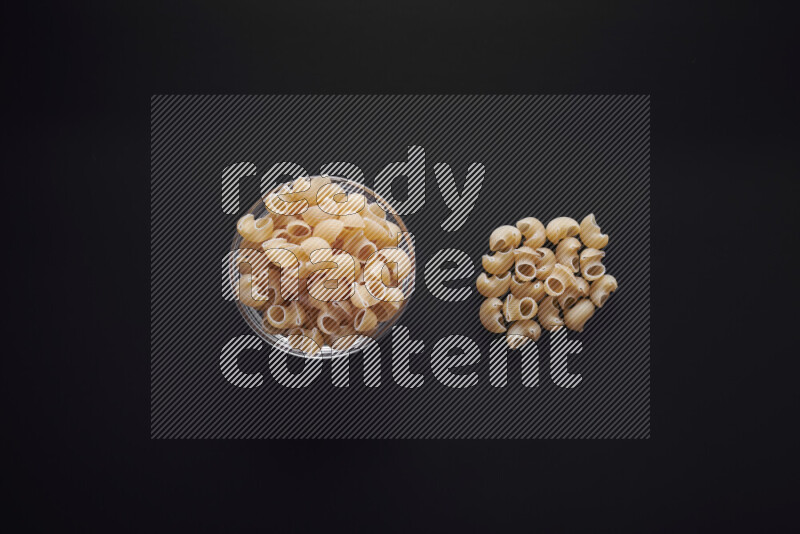 Pipe pasta in a glass bowl on black background