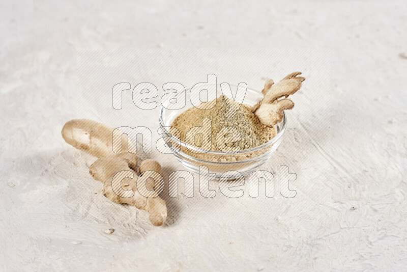 A glass bowl full of ground ginger powder on white background