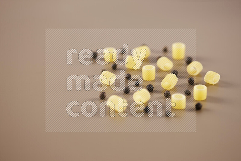 Raw pasta with different ingredients such as cherry tomatoes, garlic, onions, red chilis, black pepper, white pepper, bay laurel leaves, rosemary and cardamom on beige background