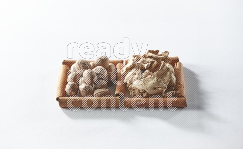 مربعان من أعواد القرفة ممتلئان بالزنجبيل المجفف وجوزة الطيب علي خلفية بيضاء