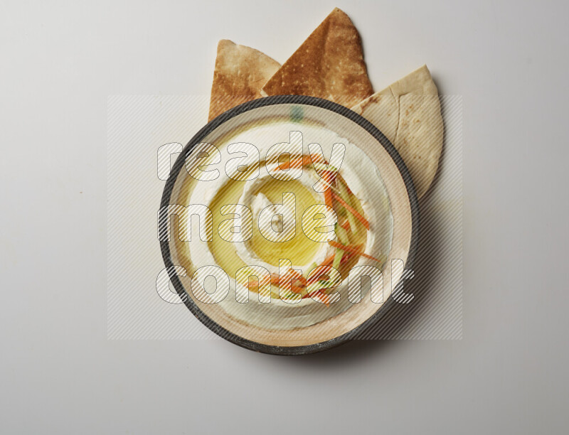 Lebnah garnished with sliced carrots &cucumber in a pottery plate on a white background