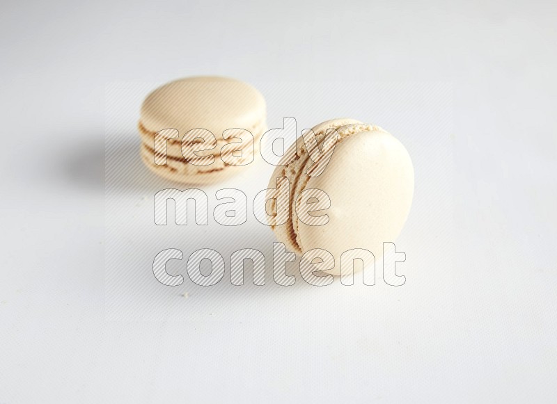 45º Shot of two White Caramel fleur de sel macarons on white background