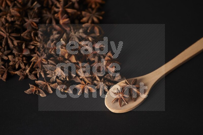 Star Anise in a wooden spoon and spreading on a black flooring