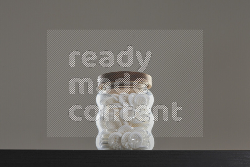 أزرار متنوعة في وعاء زجاجي علي خلفية سوداء