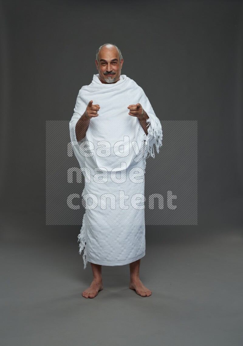 A man wearing Ehram Standing Interacting with the camera on gray background