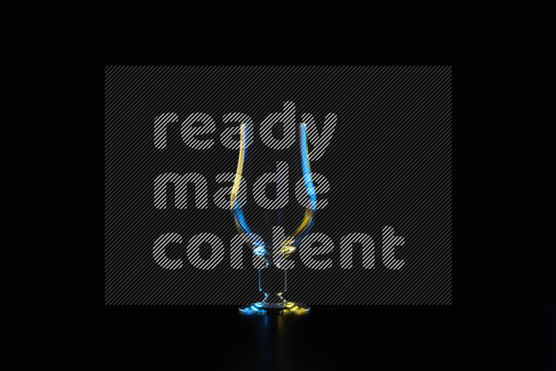 Glassware with rim light in blue and yellow against black background